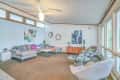 Mid-century modern living room with gray sectional, abstract art, round glass coffee table, and large windows.