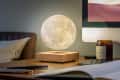 Levitating moon lamp on wooden base beside a candle, keyboard, and pens on a desk.