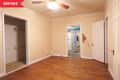 Empty room with hardwood floors, beige walls, ceiling fan, open closet, and visible damage near doorways.