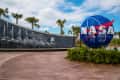 NASA globe sculpture with a fountain wall and palm trees in the background.