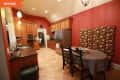 Kitchen with red walls, wooden cabinets, stainless steel fridge, and floral upholstered dining chairs around a round table.