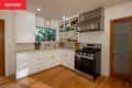 Kitchen with white cabinets, stainless steel stove, open shelves, and a window overlooking greenery.