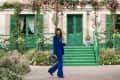 Still from Emily in Paris with Lily Collins walking by beautiful buildings in a blue velvet suit