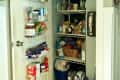 Cluttered pantry with shelves and door racks filled with various food items and cleaning supplies.