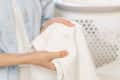 Person holding a stained white shirt near a laundry basket.