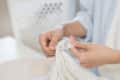Person checking care label on a white garment, focusing on washing instructions.