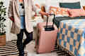 shot of someone rolling their pink suitcase out of their bedroom.