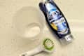 Dawn Platinum Plus PowerSuds Dish Soap, a plastic container, and a sink scrub brush