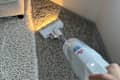 PowerClean Cordless Stick Vacuum in use on a carpeted surface.