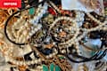 A tangled assortment of jewelry including pearl necklaces, colorful earrings, and metal chains.