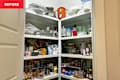 A cluttered pantry with various food items, jars, and containers on white shelves.