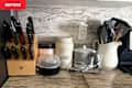 Countertop with a knife block, containers of collagen peptides and organic powder, utensils in a pitcher, and a small appliance.