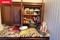 Cluttered kitchen cabinet with various canned goods, containers, and a bowl on a granite countertop.