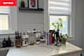 Kitchen countertop with a knife block, utensils, cookbooks, a plant, and a spice organizer.