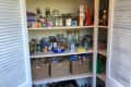 Before: white doors opening to show a large pantry with four white shelves packed with food