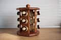 Wooden spice rack with glass jars on a kitchen counter.