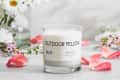 Scented candle labeled "Outdoor Fellow No.10" with pink petals and white flowers in a vase.