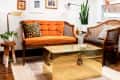 Cozy living room with orange sofa, leopard print pillows, gold coffee table, and wall art under wooden beams.
