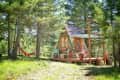 A-frame cabin with a small porch, surrounded by trees, red hammock, and outdoor seating.