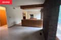 Living room before home staging. Mostly empty room with brown leather sofa, one exposed brick wall
