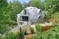 The exterior of a gray geodesic dome house.