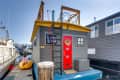 gray wood paneling on outside of house boat with bright red door and ladder access to roof