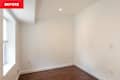 Empty room with hardwood flooring, white walls, a window with blinds, and a light fixture on the ceiling.