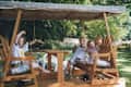 Three children joyfully waving from a wooden swing set.