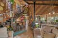 Cozy living area with wooden walls, a staircase, bar stools, and a wood stove, featuring plants and decorative items.