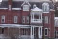 Victorian-style red brick house with snow-covered roof and ornate white trim.