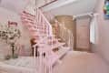 Pink staircase with decorative railings, floral decor, and a "Love" sign in a pastel-themed room.