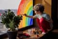 child draws rainbow in window during coronavirus