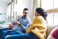 Couple sitting on couch at home sitting on couch and sharing mobile phone
