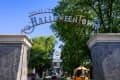 Entrance to Spirit of Halloweentown with stone pillars, trees, and a festive archway.