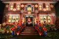 Brick house adorned with Christmas lights, nutcracker statues, and snowflake decorations on windows and walls.