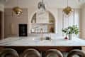 Kitchen with pale neutrals, brass hardware, and a marble alcove and countertop