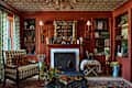 Cozy living room with red walls, a patterned ceiling, a fireplace, and a checkered armchair, adorned with books and decor.
