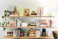 Wooden shelves with books, framed art, plants, decorative figurines, and a lamp, creating a cozy and eclectic display.
