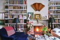 Cozy living room with a fireplace, bookshelves, blue velvet chair, and tulips on a coffee table.