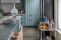 Modern kitchen with blue cabinets, terrazzo backsplash, glass decanter, and a bar cart with assorted drinks and fruits.