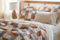 Patchwork quilt and pillows in blue, orange, and white on a bed with a wooden headboard, next to a ceramic lamp.