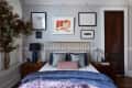View of a bedroom with a brass bed and framed prints hanging behind the bed
