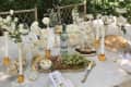 Product photo of Vixdonos Taper Glass Candlestick Holders in amber color, shown on outdoor dining table with wine, flowers, cheese board