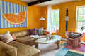 Living room with orange, blue and large watch on the wall.