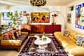 Bright living room featuring a striped sofa with decorative pillows, a yellow leather couch, a white coffee table, and a patterned rug.