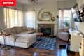 Living room with a beige sectional sofa, stone fireplace, round coffee table, and a TV mounted on the wall.