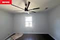 Empty room with light blue walls, dark hardwood floor, a ceiling fan, and a window. A drop cloth is on the floor.