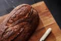 Sourdough loaf and serrated knife on a wooden cutting board.