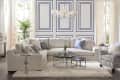 Elegant living room with a beige sectional sofa, patterned armchair, glass coffee tables, and blue-accented wall panels.