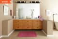 Bathroom with wooden vanity, large mirror, pink rug, and wall art.
